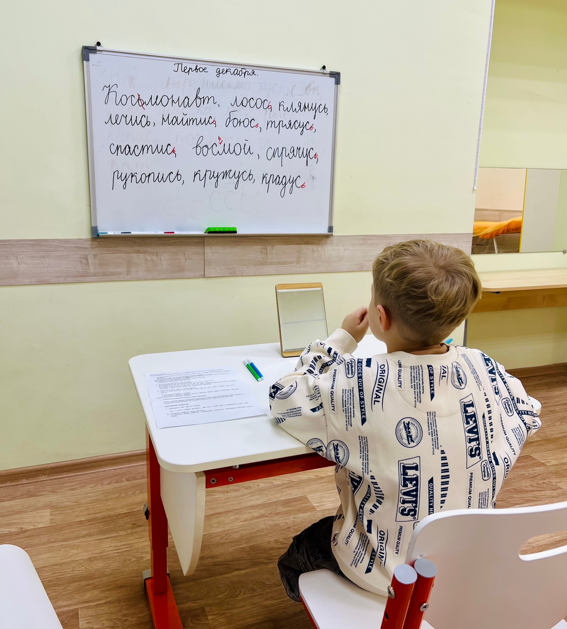 Ребёнок выполняет упражнения на письмо у маркерной доски