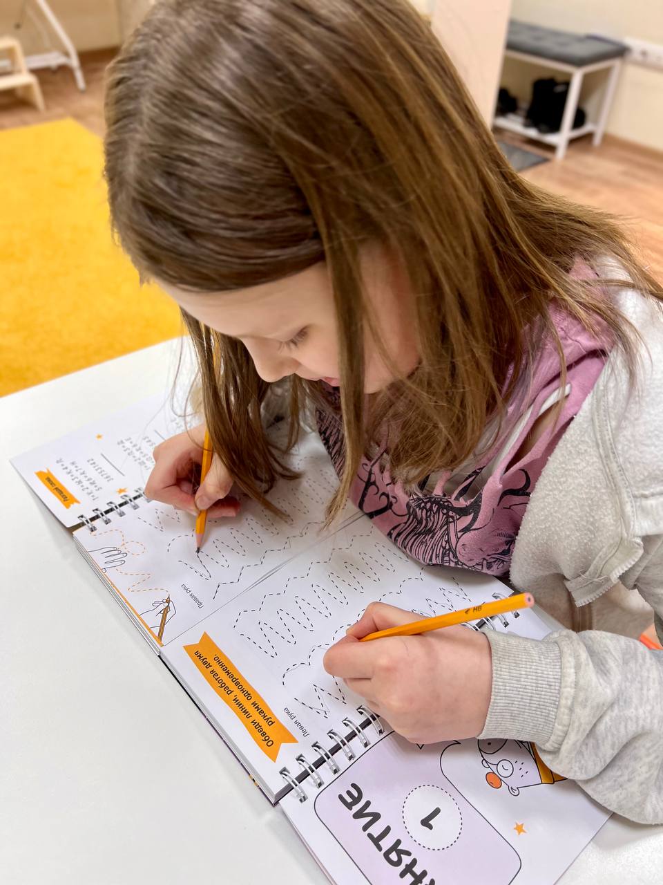 Девочка выполняет письменные задания по рабочей тетради логопеда